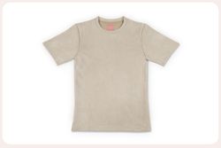 A beige suede T-shirt laid flat against a clean, bright white background with rounded frame edges. The shirt has a soft, velvety texture and a small pink tag inside the collar. The photo looks edited and professional, ready to be used for a webshop.